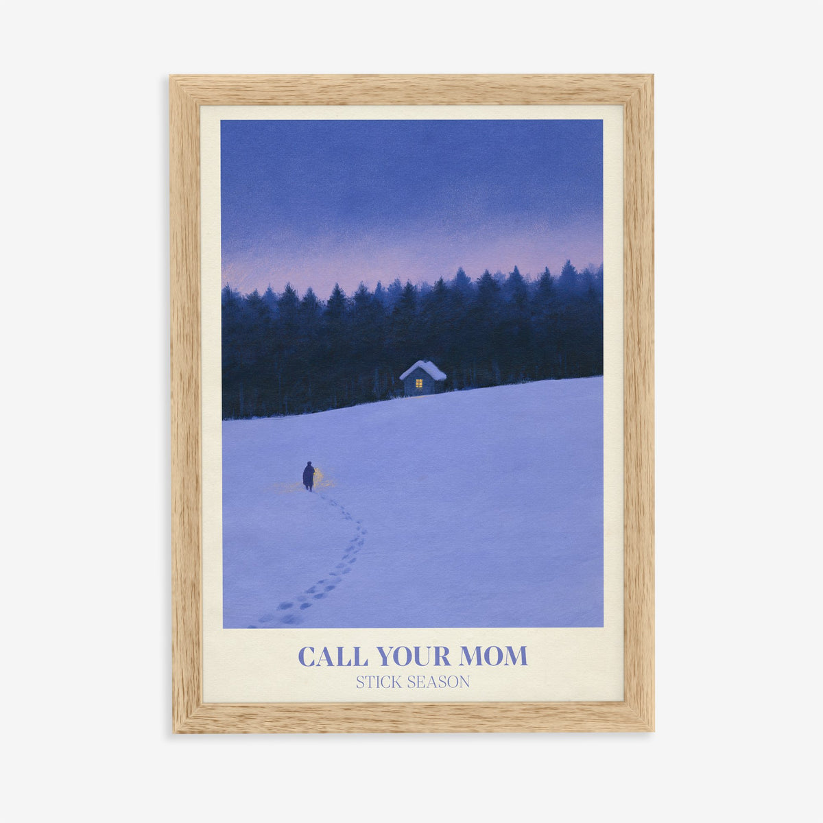 Call Your Mom Winter Noah Kahan print of a lone walker heading to a lit cabin in the snow, in an oak frame on a plain wall