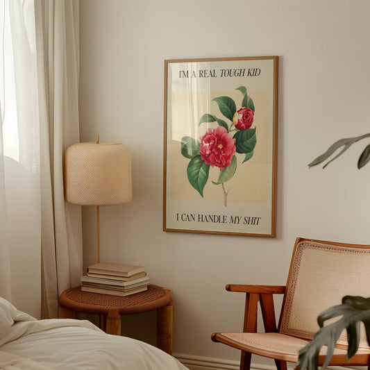 Im A Real Tough Kid I Can Handle My Shit Taylor Swift print of a red camellia on pale yellow, framed above a side table and lamp
