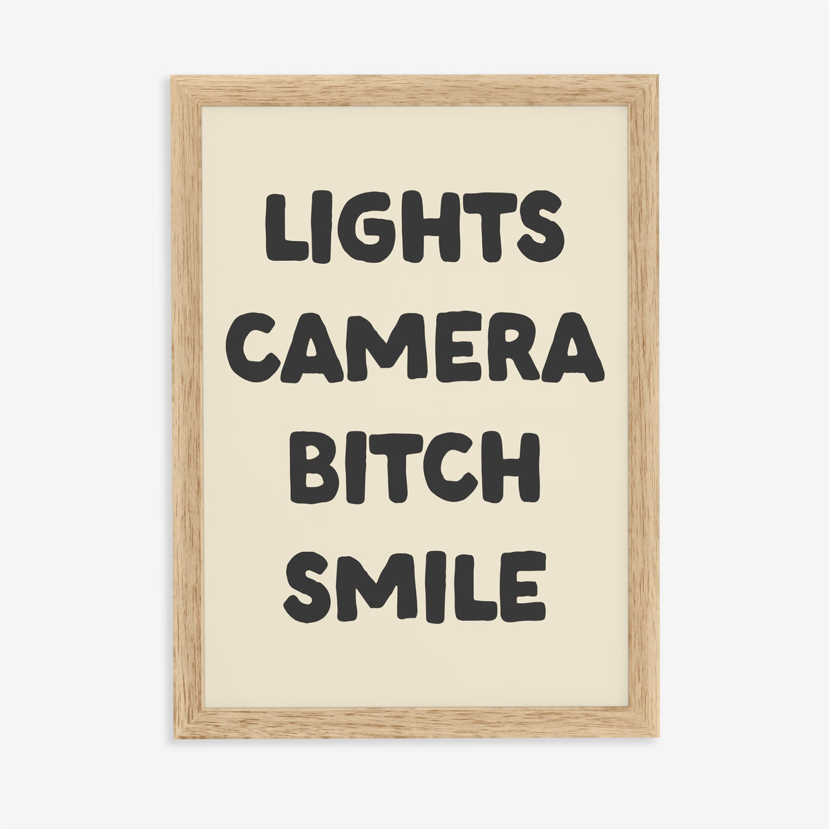 Lights Camera Bitch Smile Taylor Swift lyric print of bold black lettering on cream, in an oak frame on a plain wall