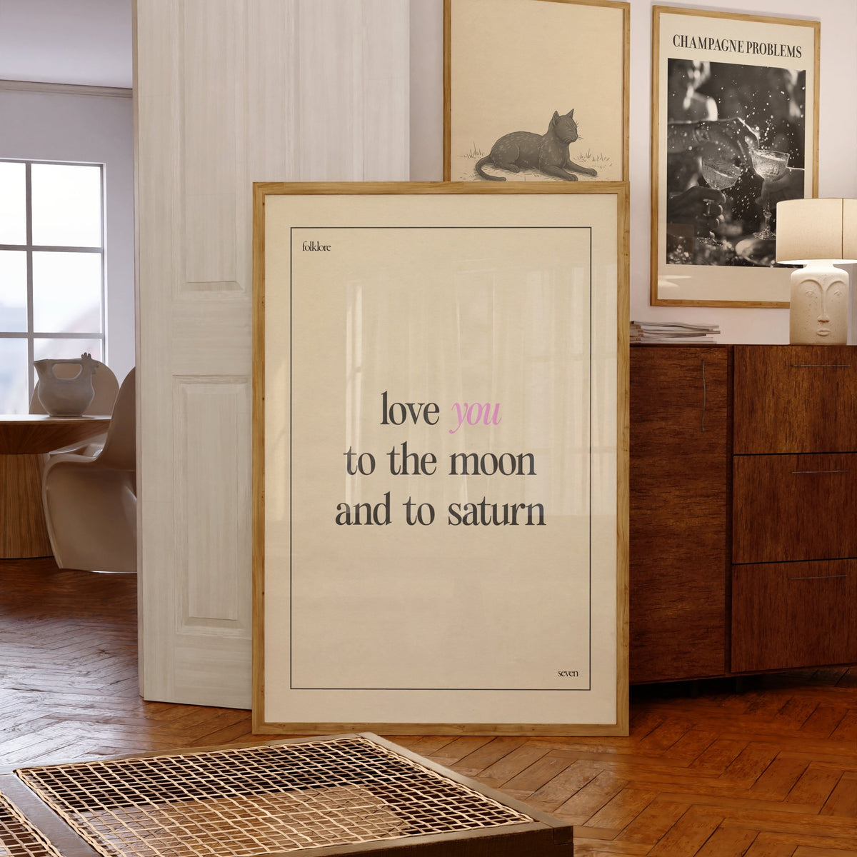 Love You To The Moon Taylor Swift print of the lyric in black and pink type on cream, framed, leaning against a chest of drawers
