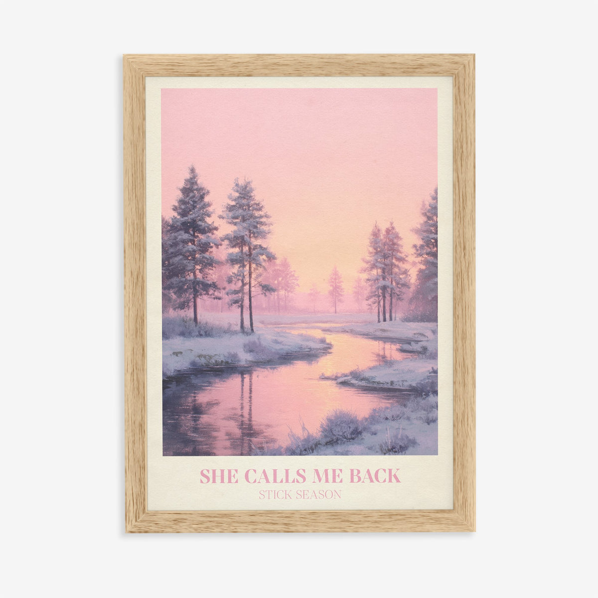 She Calls Me Back Noah Kahan print of a frosty river winding between pines under a pink sky, in an oak frame on a plain wall