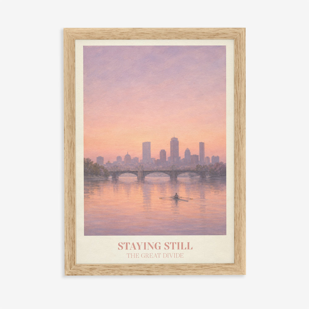 Staying Still Noah Kahan print of a lone rower on a pink river below a city skyline, in an oak frame on a plain wall