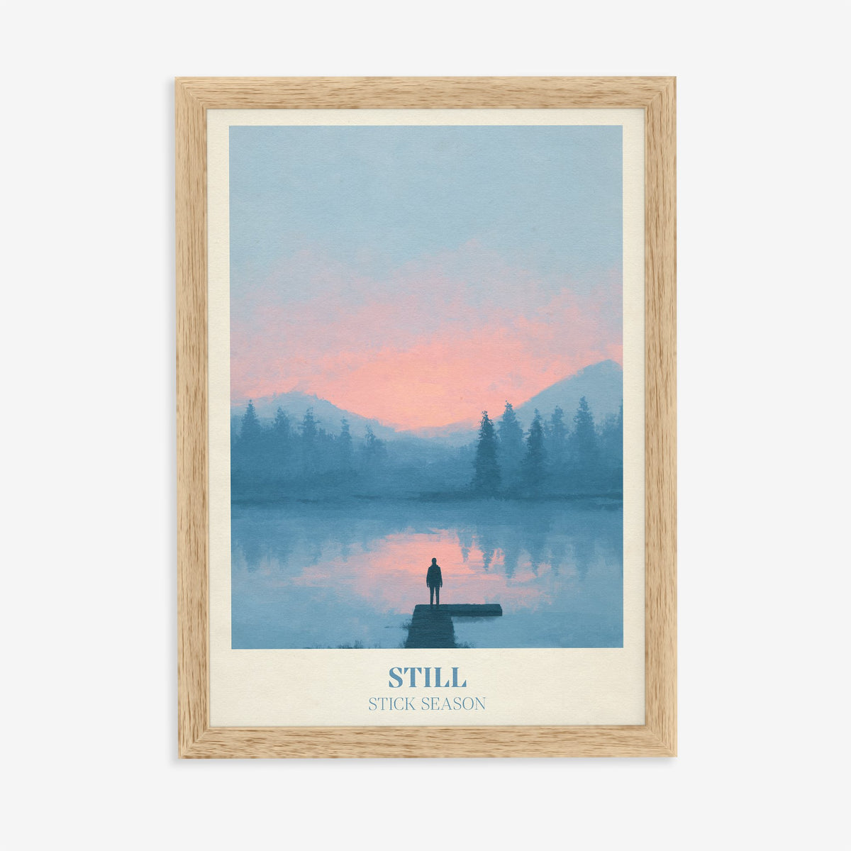 Still Noah Kahan print of a lone figure on a jetty over a pink and blue lake, in an oak frame on a plain wall