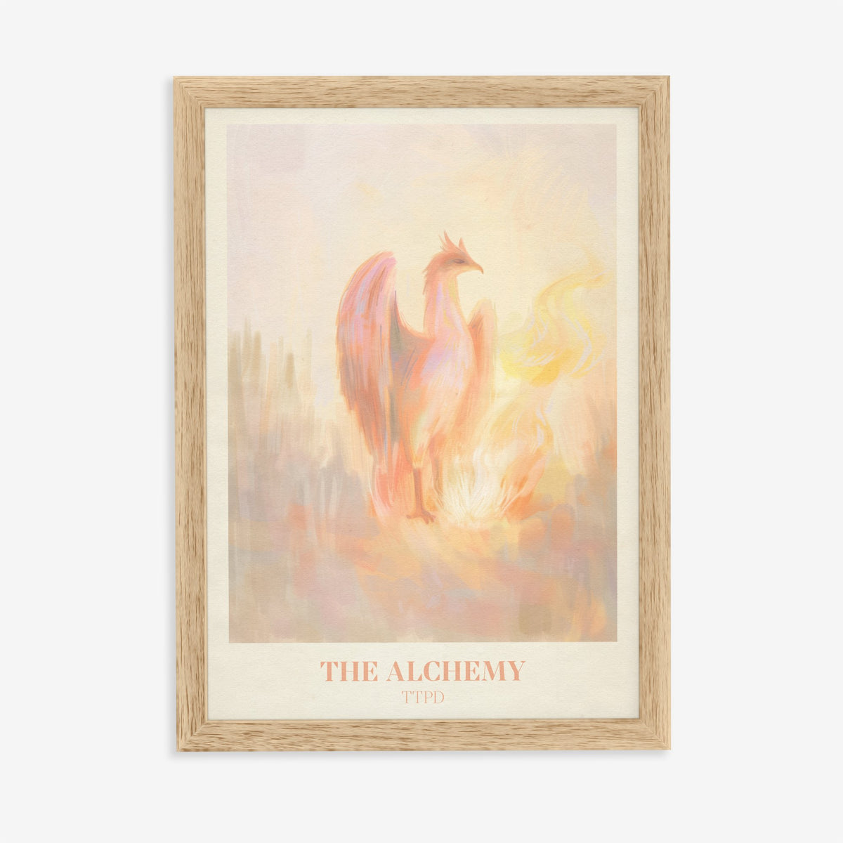 The Alchemy Taylor Swift print of a pink and peach phoenix rising beside golden flames, in an oak frame on a plain wall