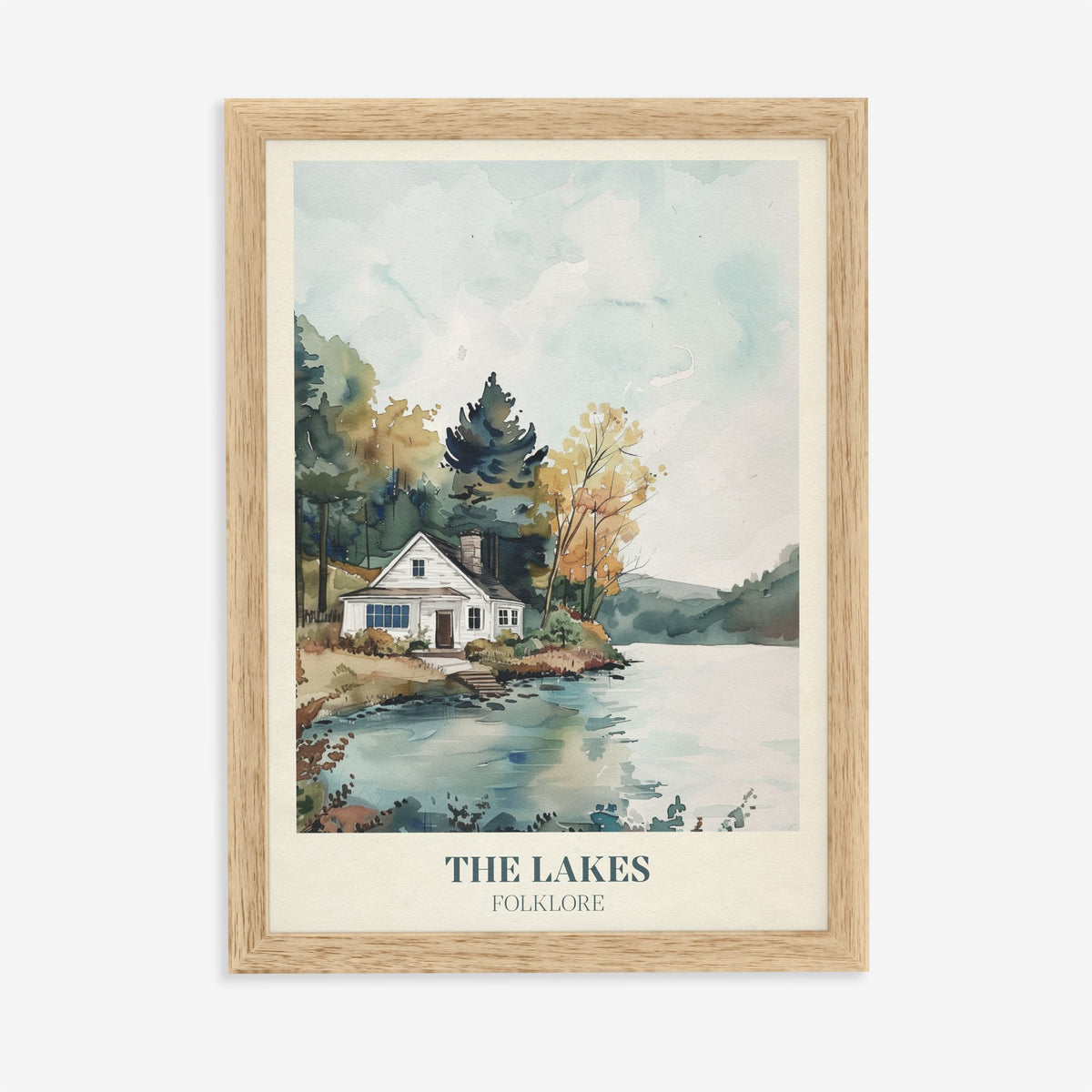 The Lakes Taylor Swift print of a white cottage beside a still lake and trees, in an oak frame on a plain wall