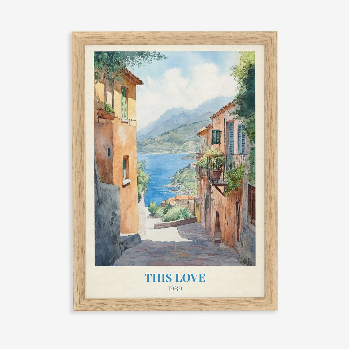 This Love Taylor Swift print of a stone lane between terracotta houses down to a blue bay, in an oak frame on a plain wall