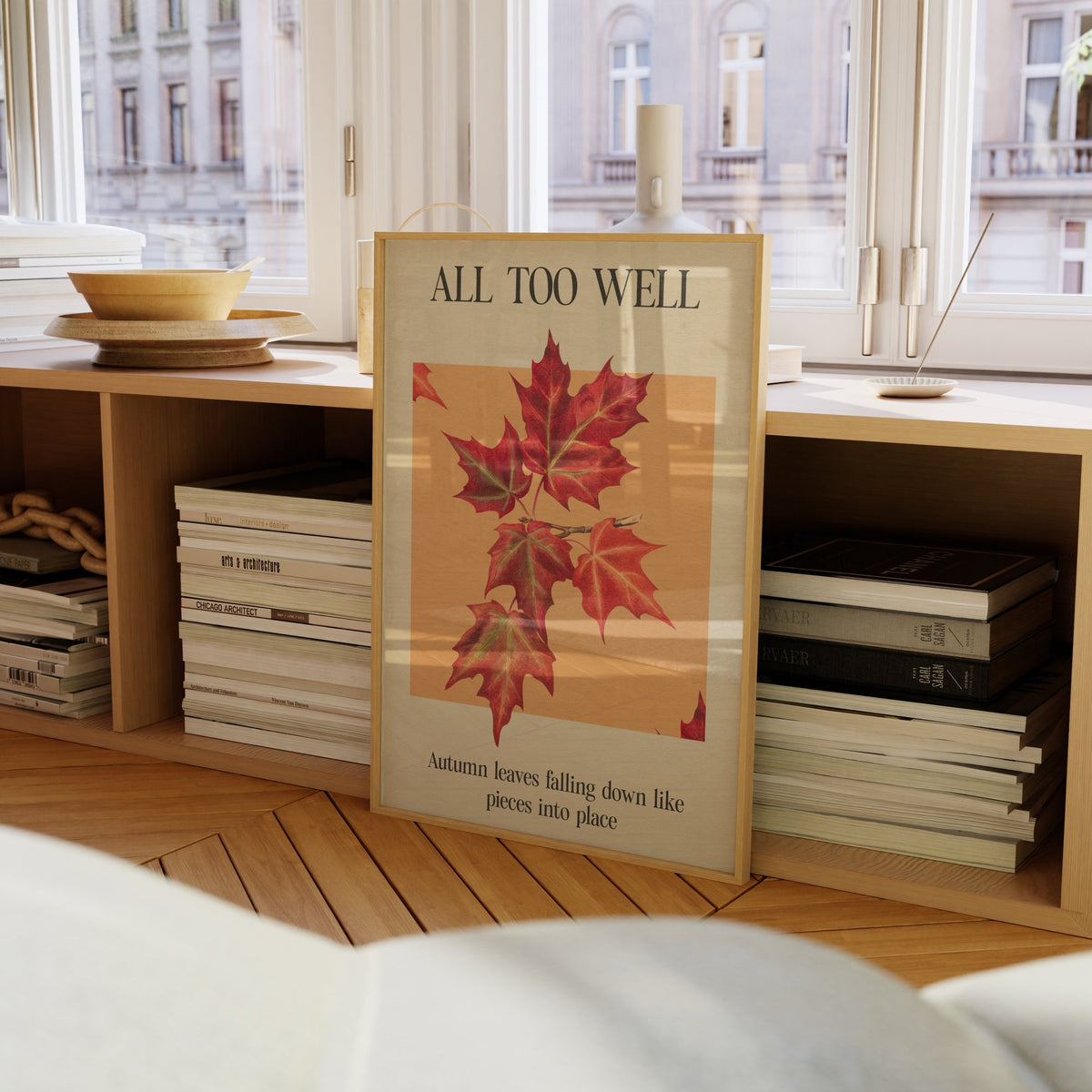 All Too Well Leaf Taylor Swift print of red maple leaves on a peach square, framed on a bookcase by a window