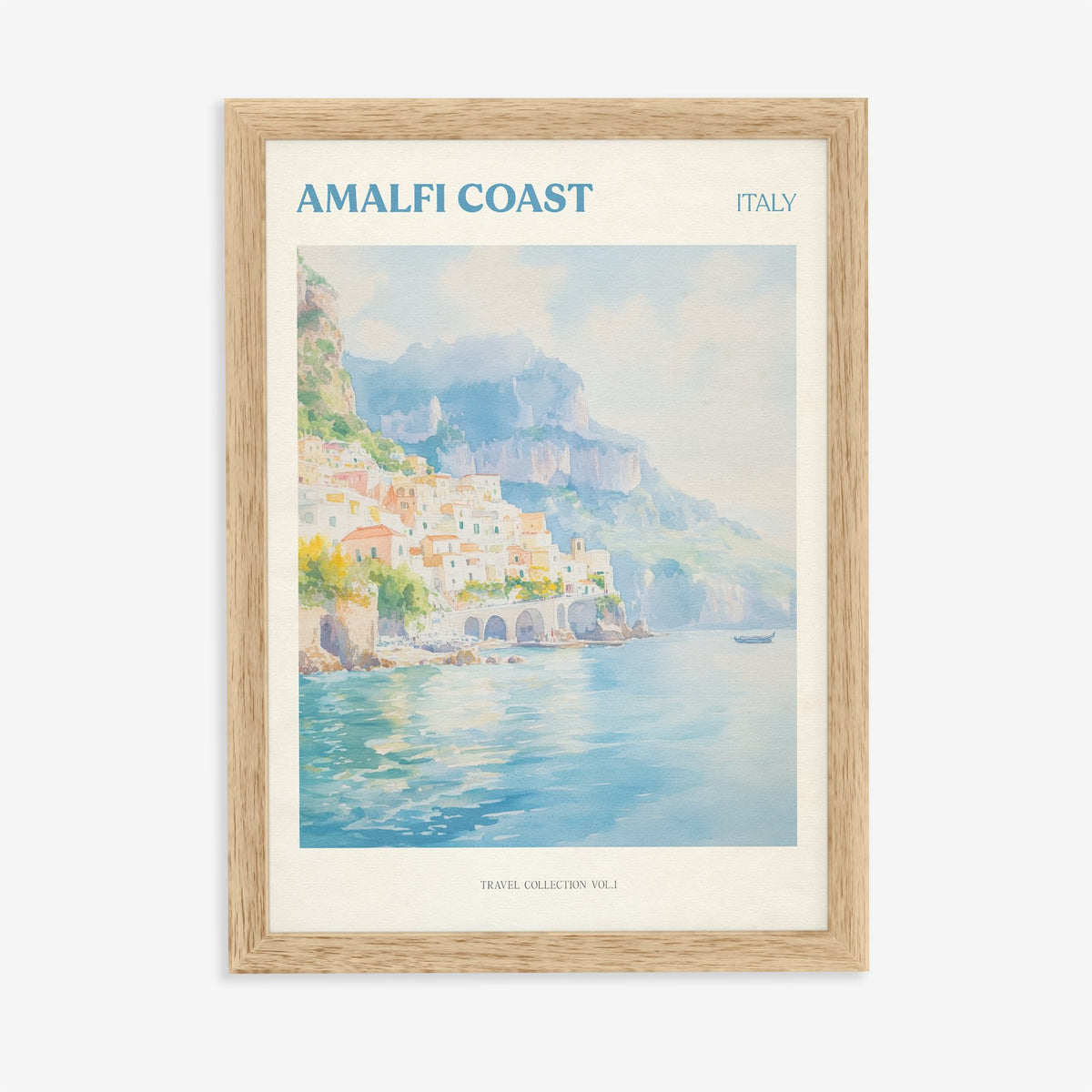Amalfi Coast travel print of pastel houses on the cliffs above a turquoise sea, in an oak frame on a plain wall