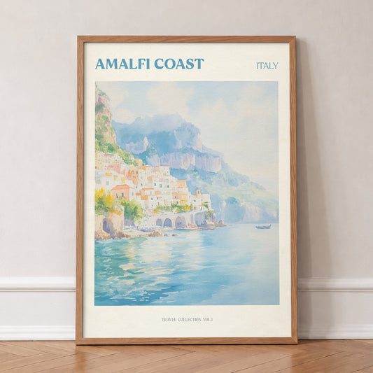 Amalfi Coast travel print of pastel houses on the cliffs above a turquoise sea, in an oak frame, leaning against a wall on a herringbone floor
