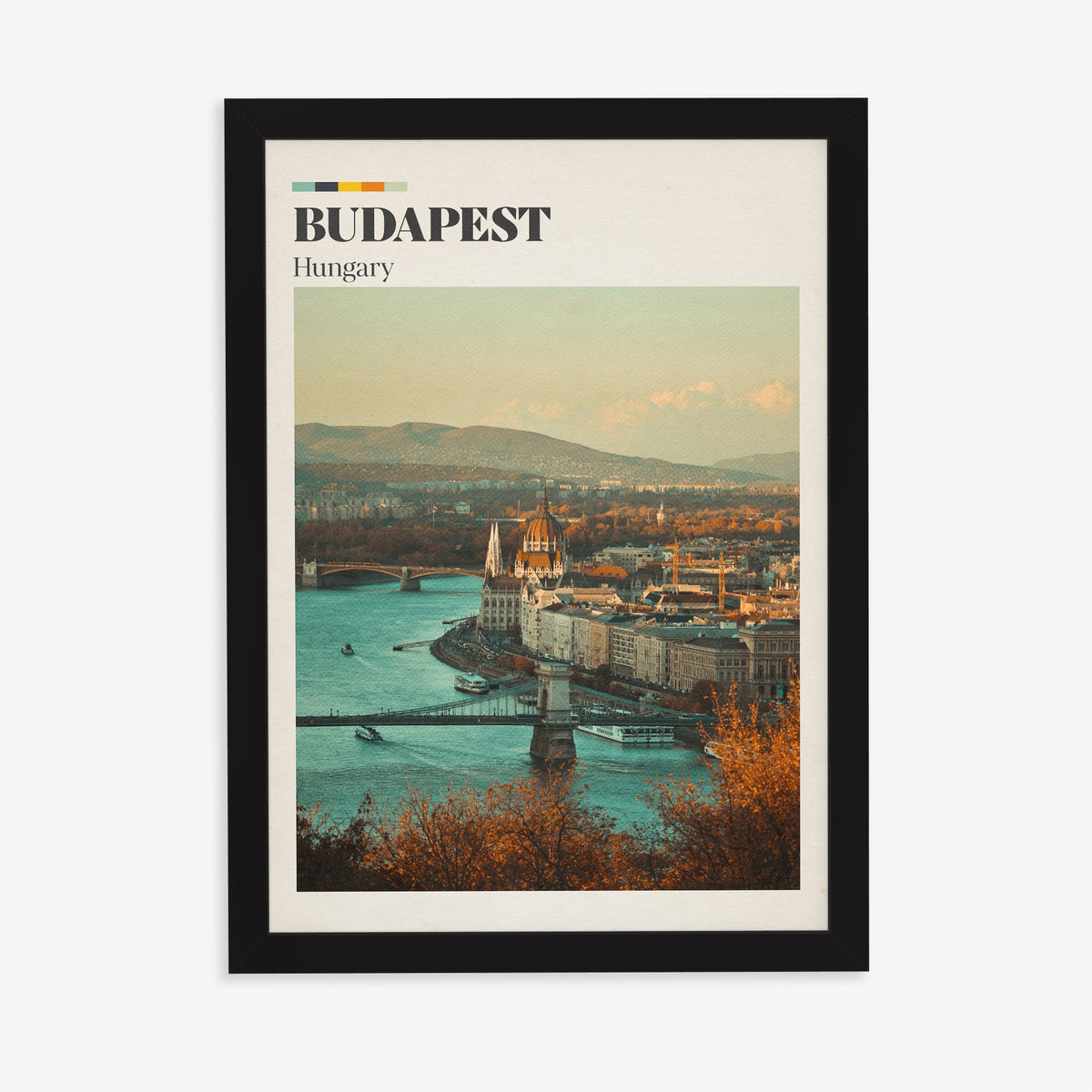 Budapest travel print of the Parliament dome above the Danube, framed by autumn trees, in a black frame on a plain wall