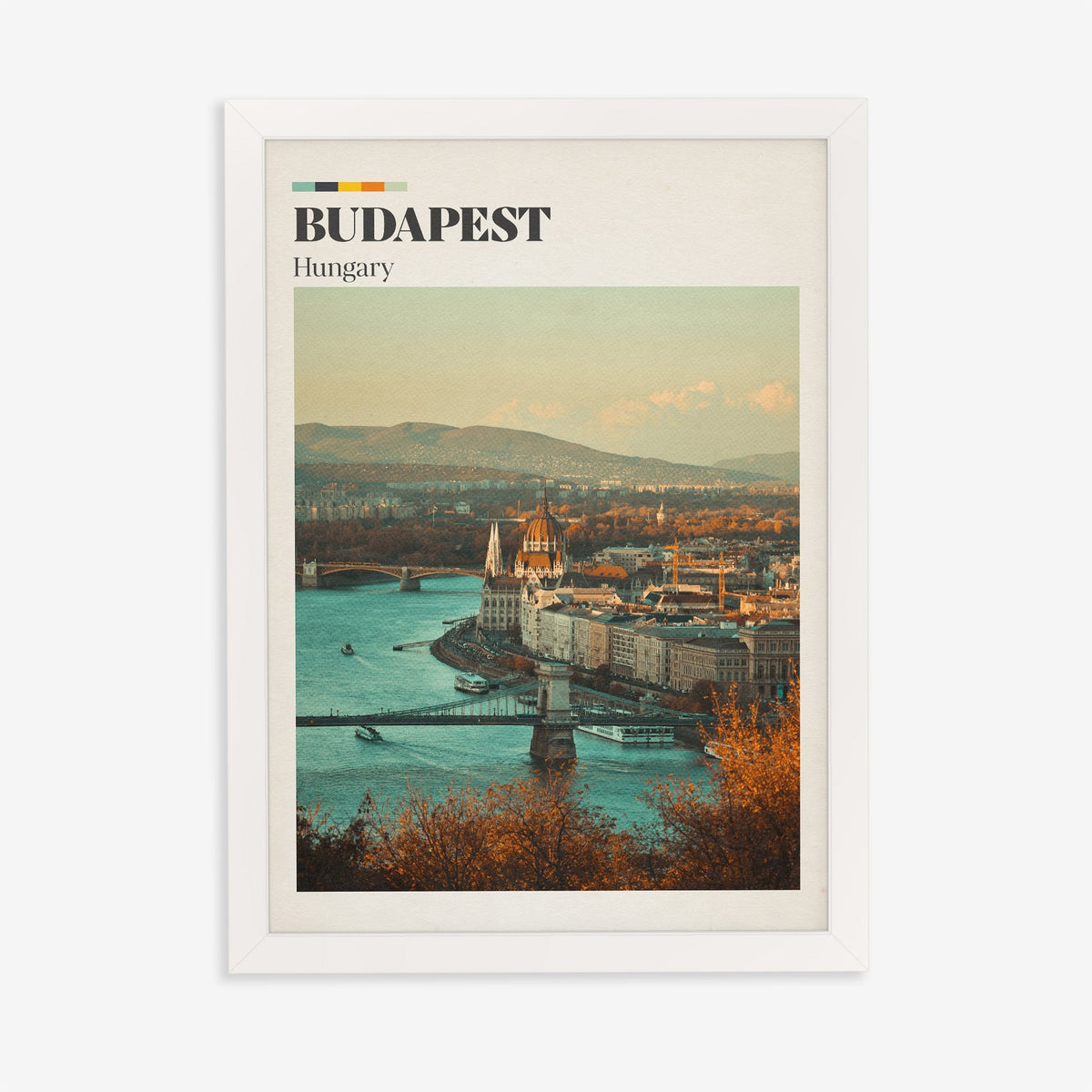 Budapest travel print of the Parliament dome above the Danube, framed by autumn trees, in a white frame on a plain wall