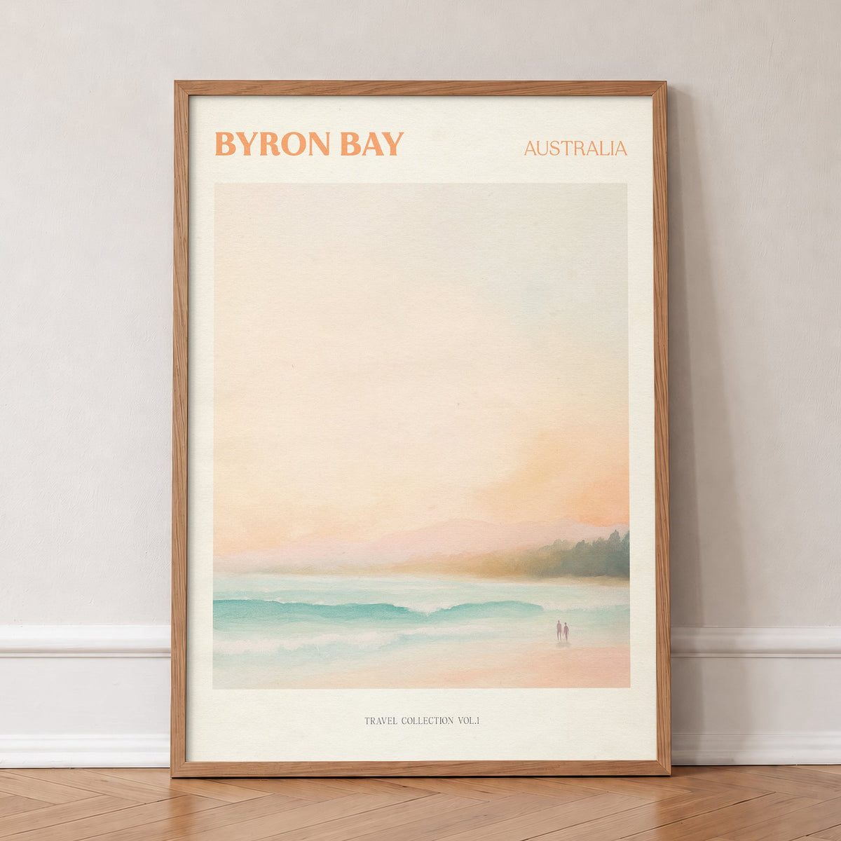 Byron Bay travel print of a pastel beach at first light with two people on the sand, in an oak frame, leaning against a wall on a herringbone floor