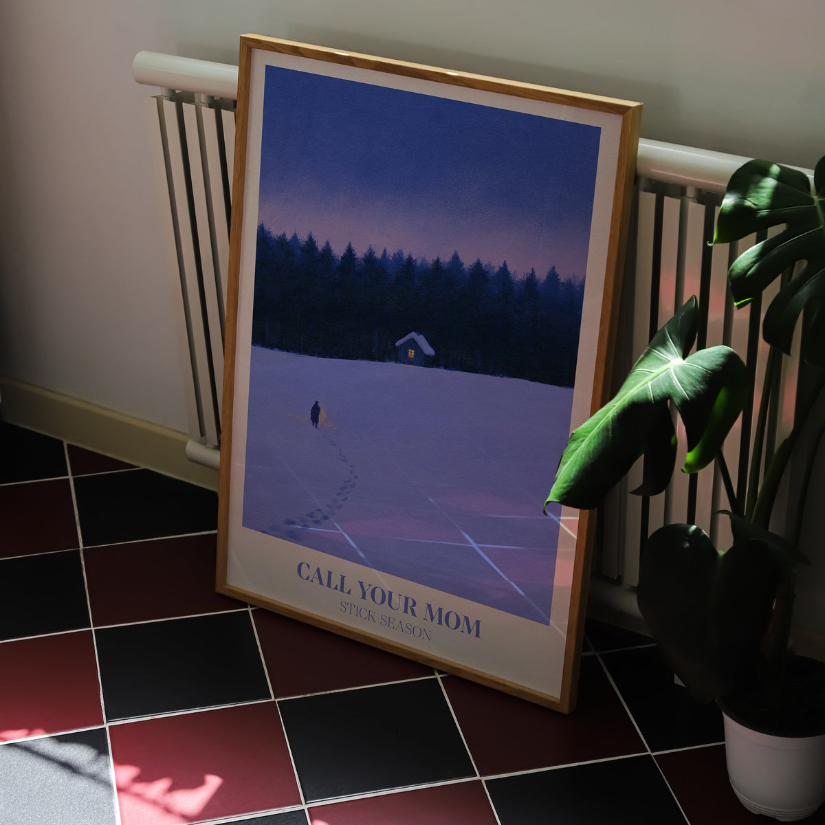 Call Your Mom Winter Noah Kahan print of a lone walker heading to a lit cabin in the snow, on a kitchen floor with red and black tiles