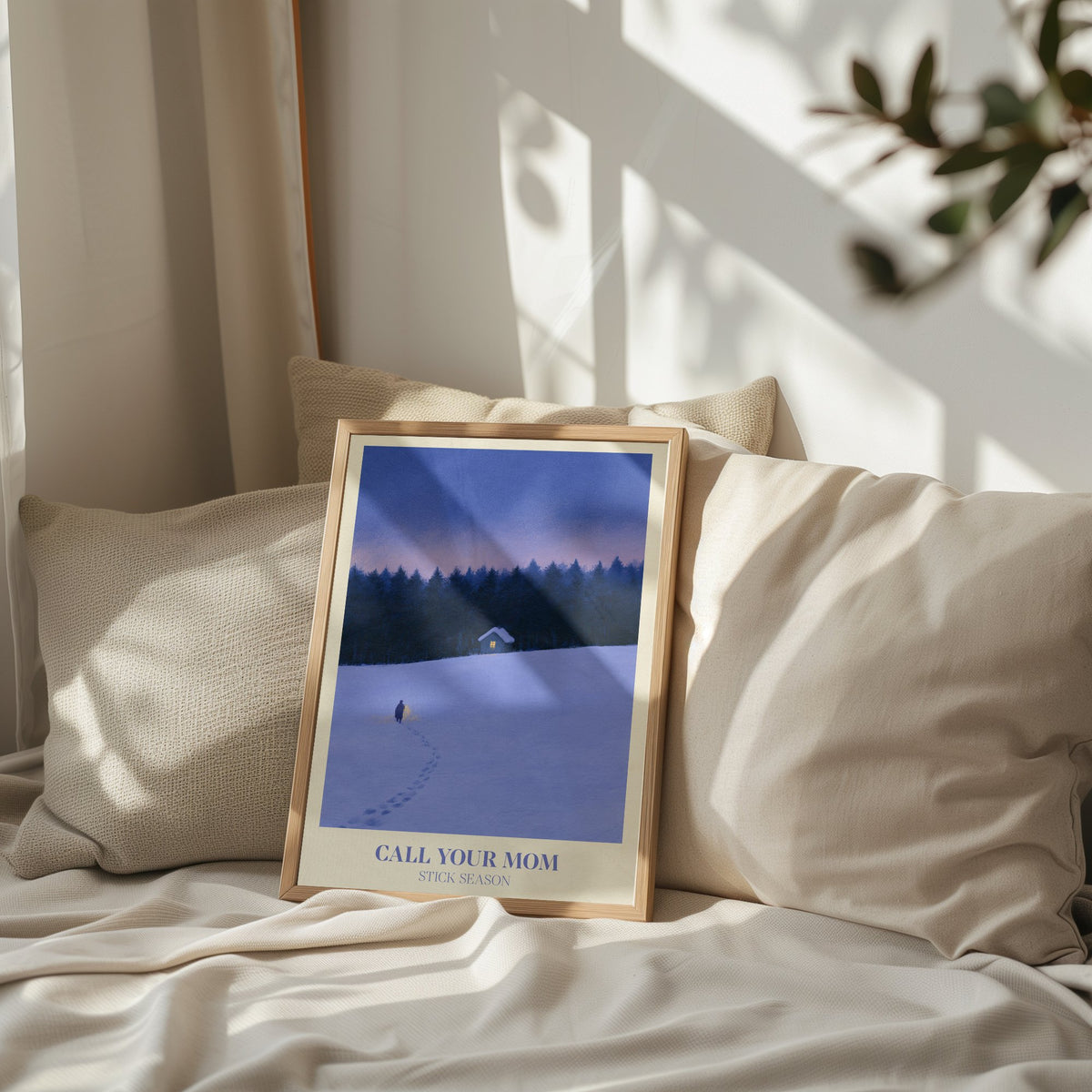 Call Your Mom Winter Noah Kahan print of a lone walker heading to a lit cabin in the snow, leaning on a bed against pillows