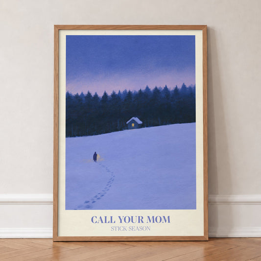 Call Your Mom Winter Noah Kahan print of a lone walker heading to a lit cabin in the snow, in an oak frame, leaning against a wall