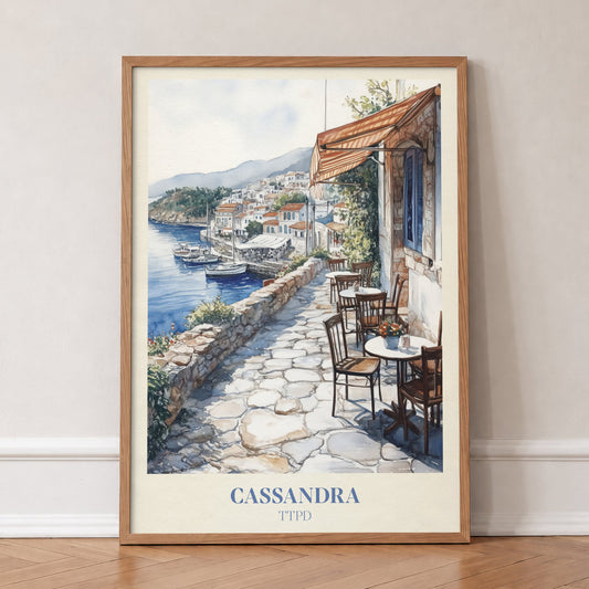 Cassandra Taylor Swift print of a cobbled café terrace above a whitewashed harbour town, in an oak frame, leaning against a wall on a herringbone floor