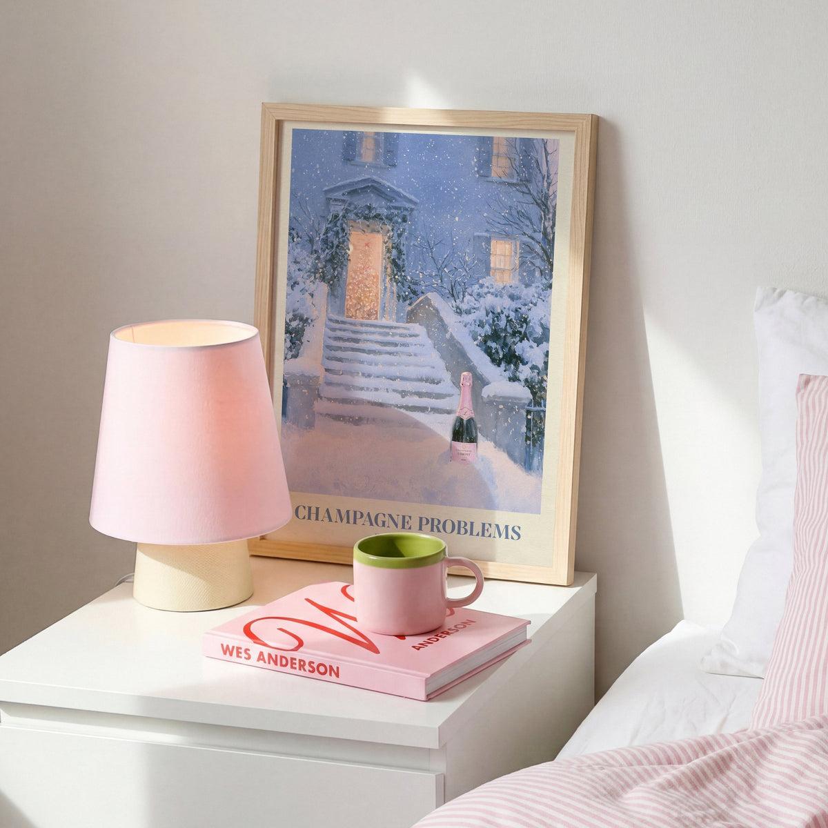 Champagne Problems Winter Taylor Swift print of champagne on snowy steps, on a white bedside table beside a pink lamp