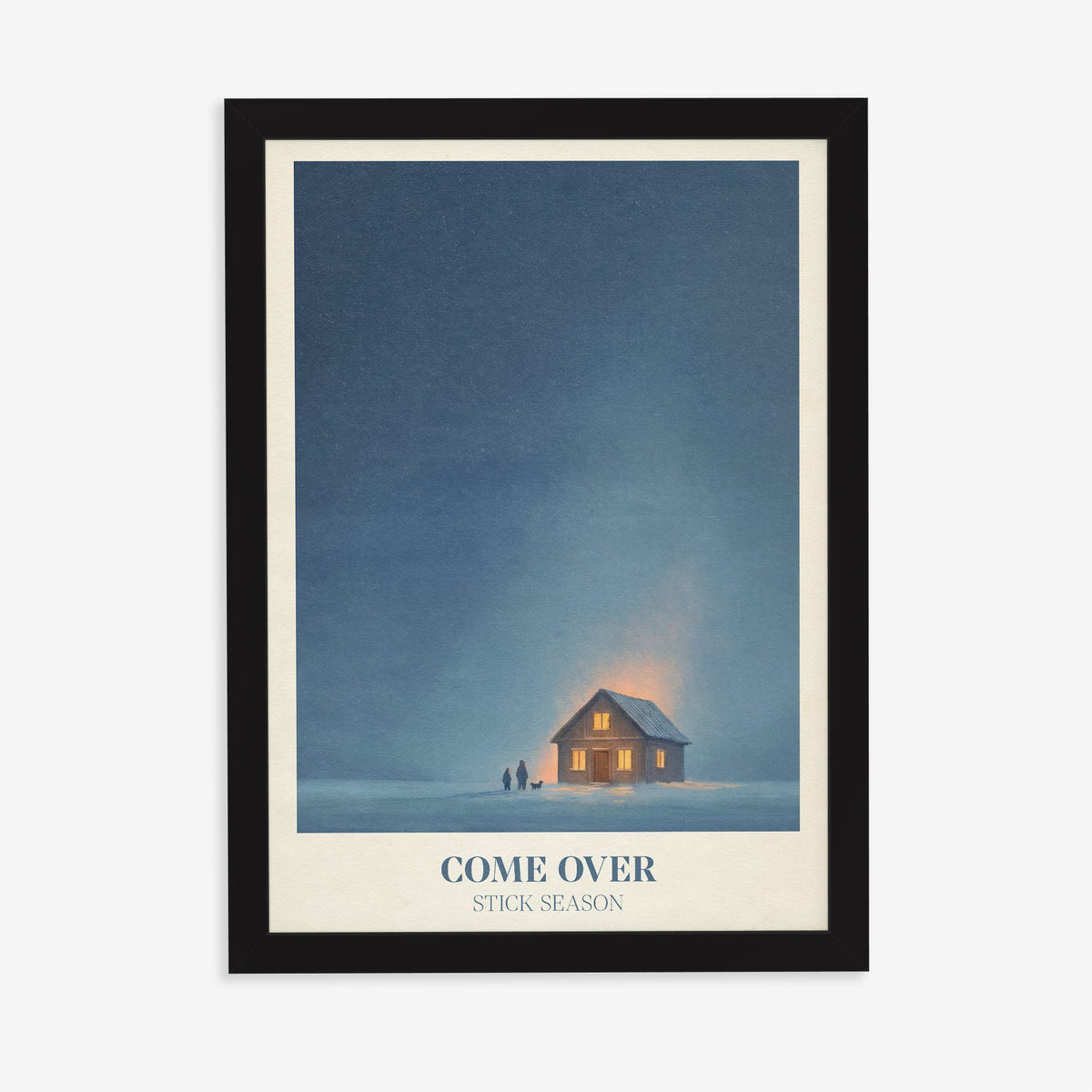 Come Over Noah Kahan print of a warm glowing cabin under a deep blue winter sky, in a black frame on a plain wall