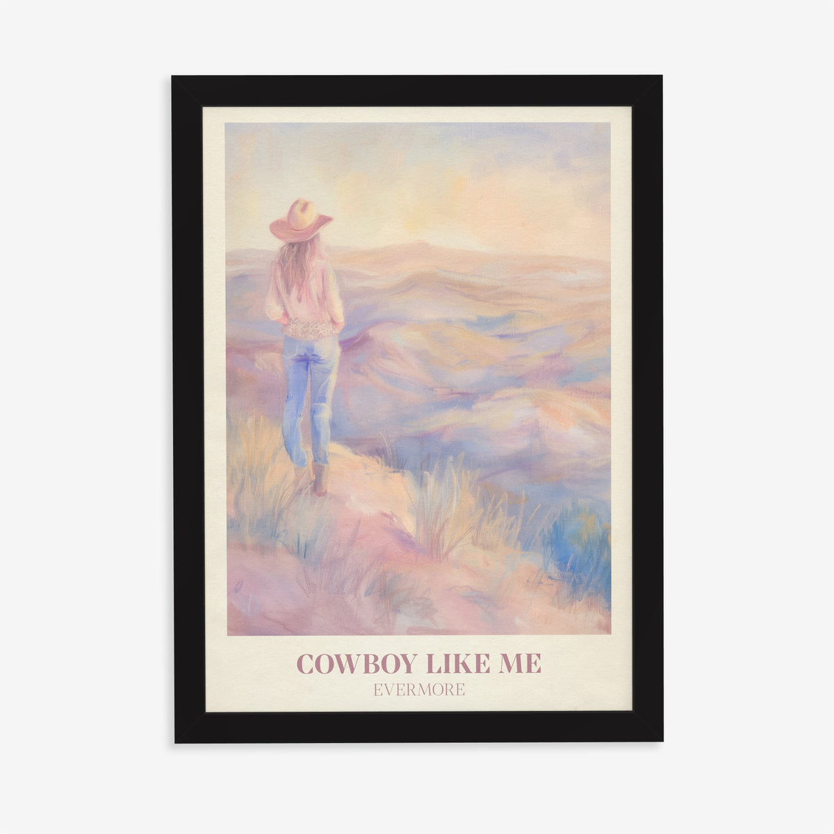 Cowboy Like Me Taylor Swift print of a cowgirl looking out over pastel hills at sunset, in a black frame on a plain wall