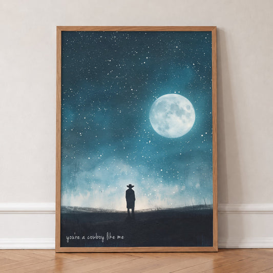 Cowboy Like Me Full Moon Taylor Swift print of a lone cowboy under a full moon and stars, in an oak frame, leaning against a wall on a herringbone floor