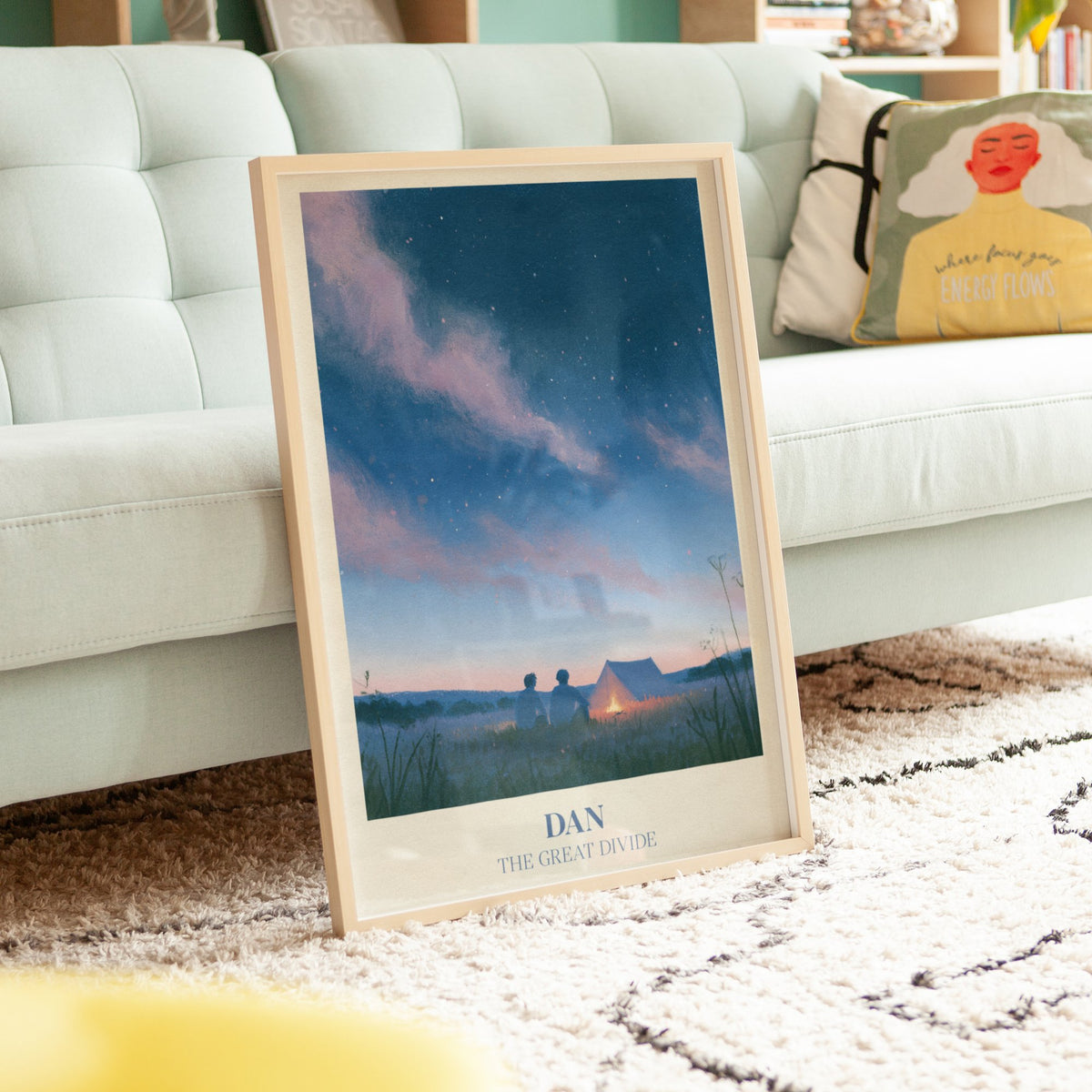 Dan Noah Kahan print of two friends by a campfire under the stars, framed, leaning against a mint sofa