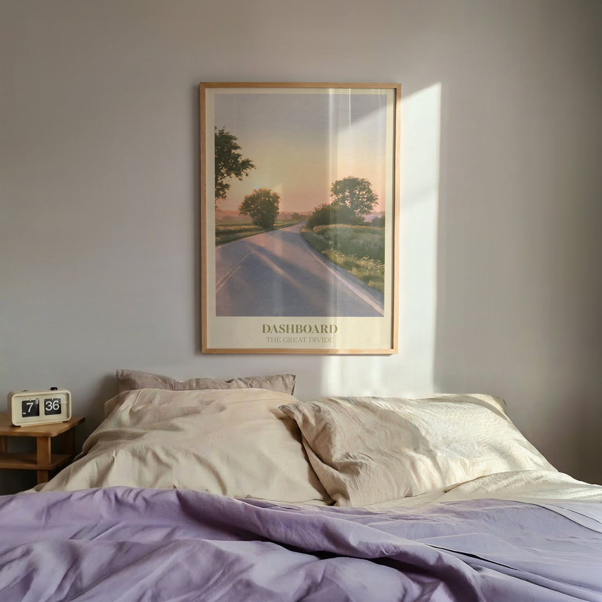 Dashboard Noah Kahan print of an empty country road at sunset, framed above a bed with lilac bedding