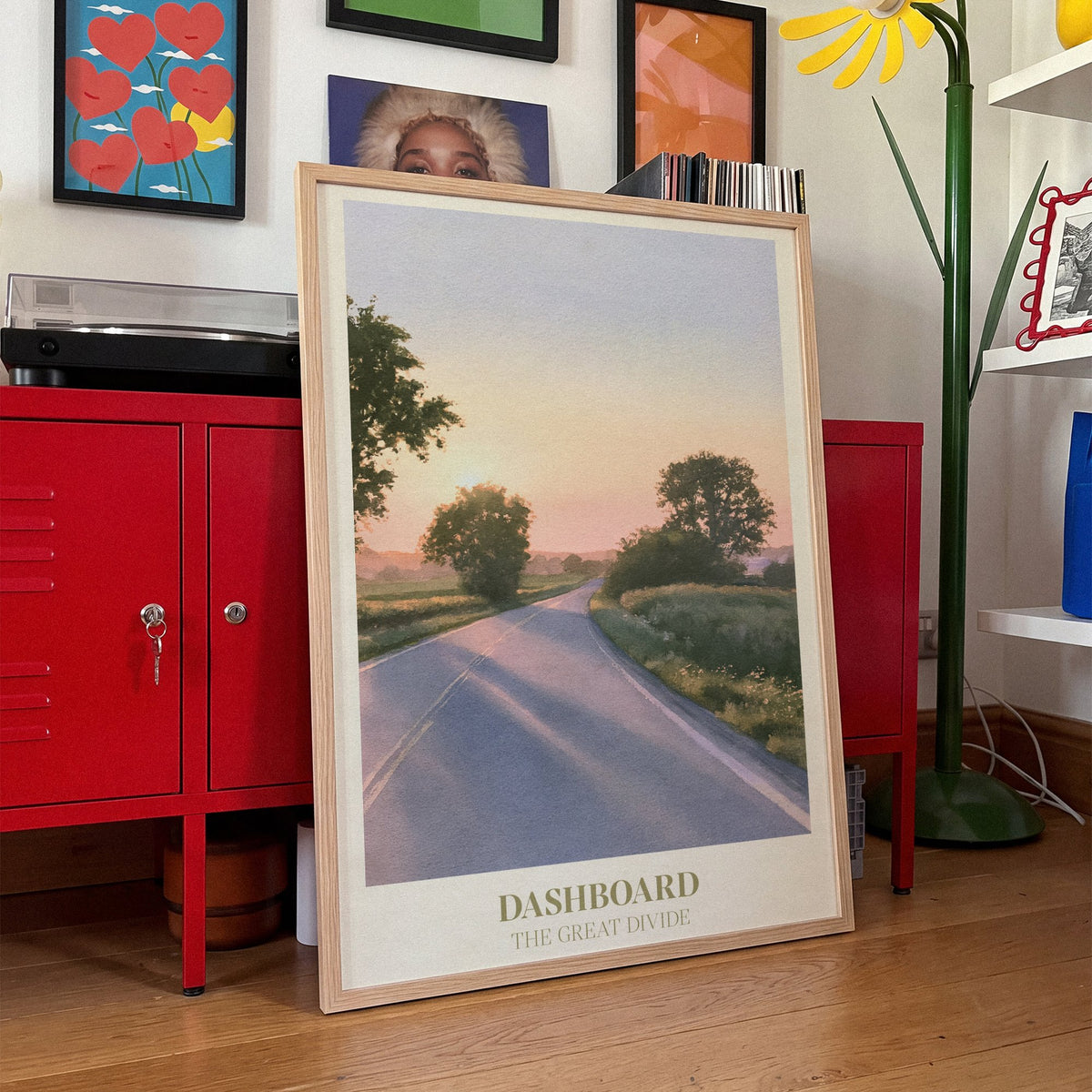 Dashboard Noah Kahan print of an empty country road at sunset, framed, leaning against red lockers