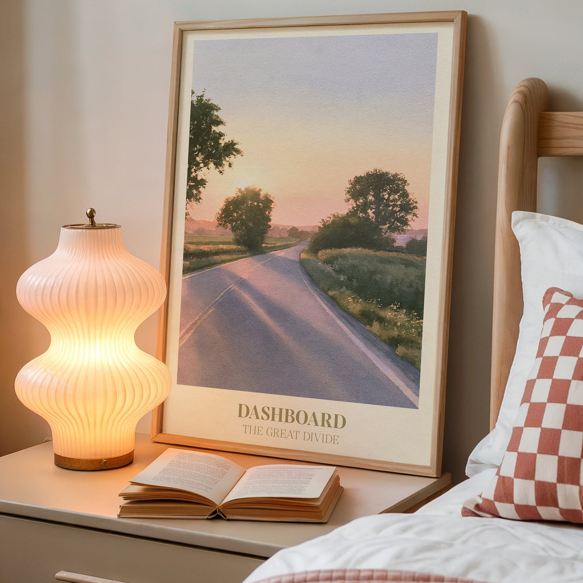 Dashboard Noah Kahan print of an empty country road at sunset, framed on a bedside table beside a lamp