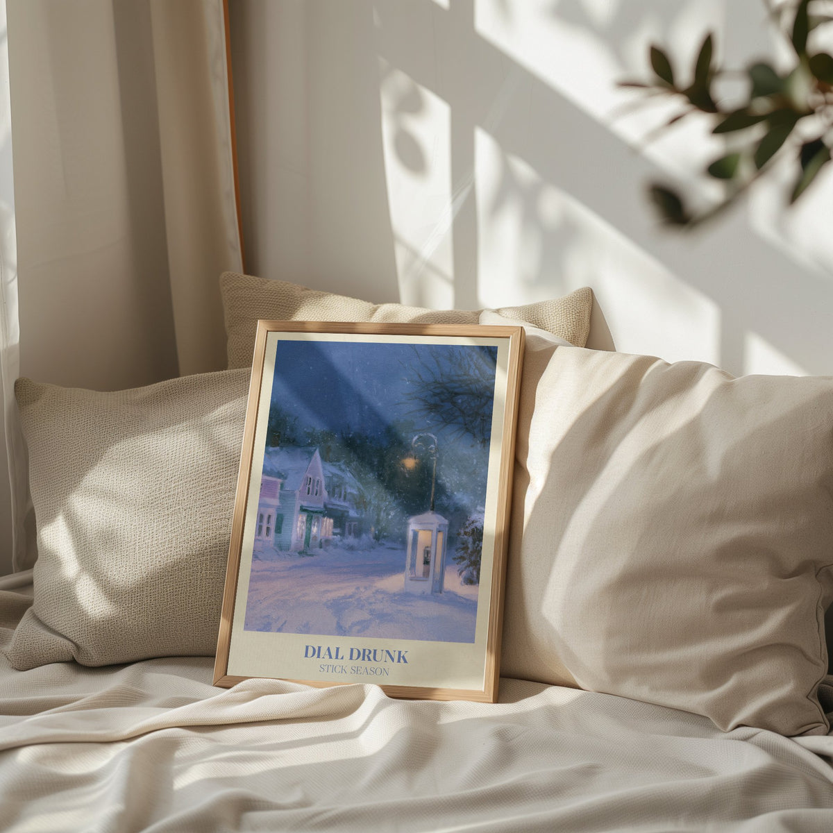 Dial Drunk Noah Kahan print of a phone box on a snowy village street at night, leaning on a bed against pillows