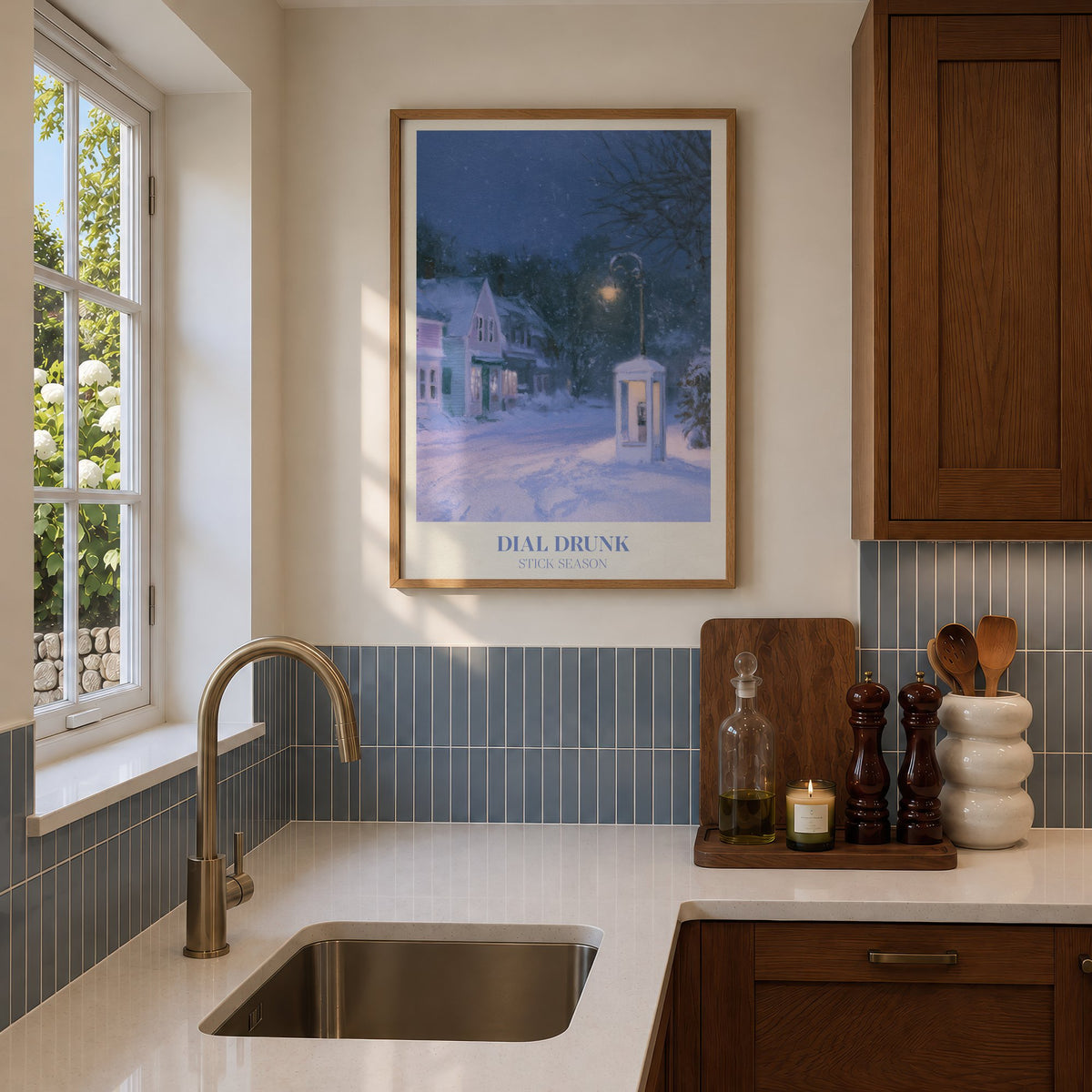 Dial Drunk Noah Kahan print of a phone box on a snowy village street at night, hung in a sunlit kitchen with blue tiles