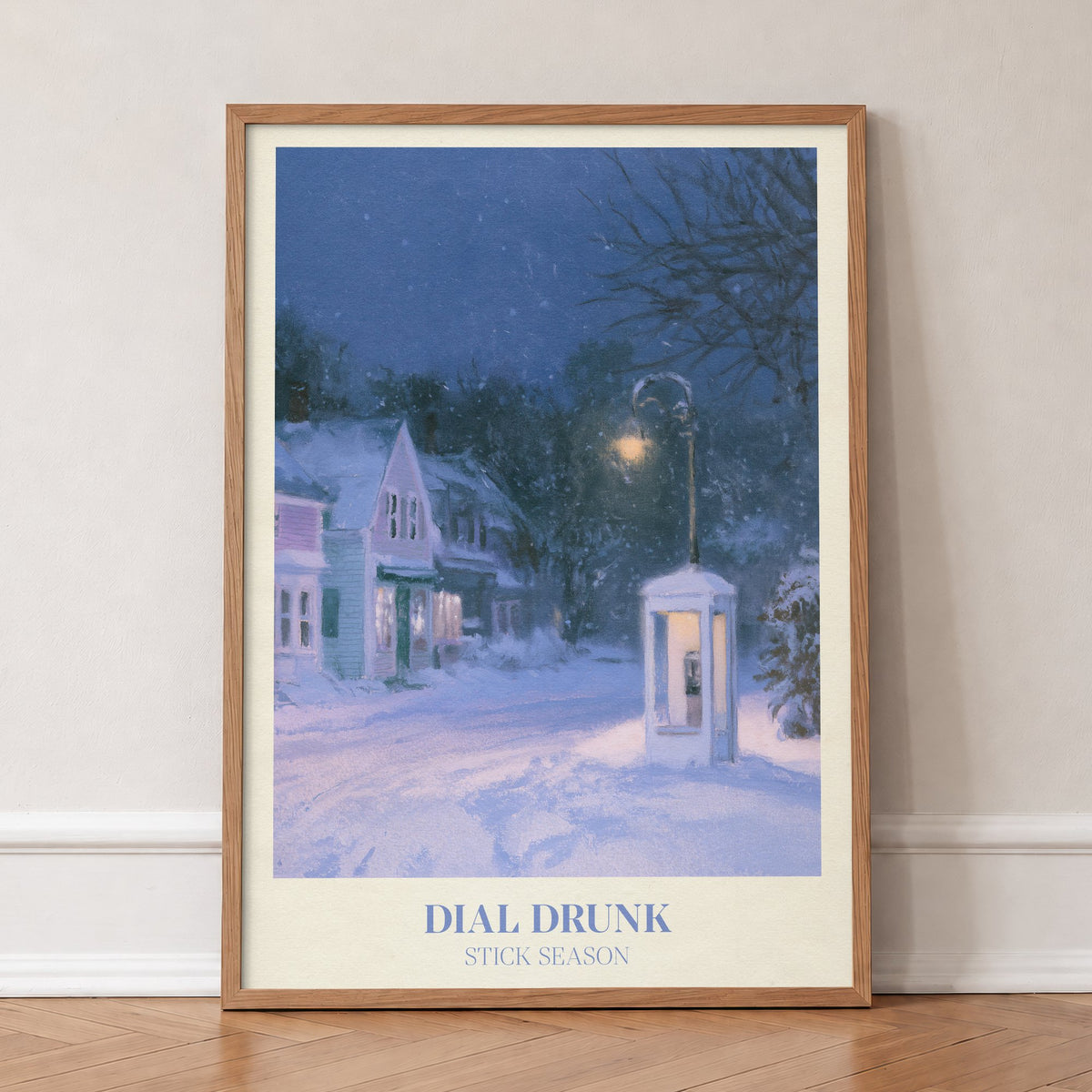 Dial Drunk Noah Kahan print of a phone box on a snowy village street at night, in an oak frame, leaning against a wall