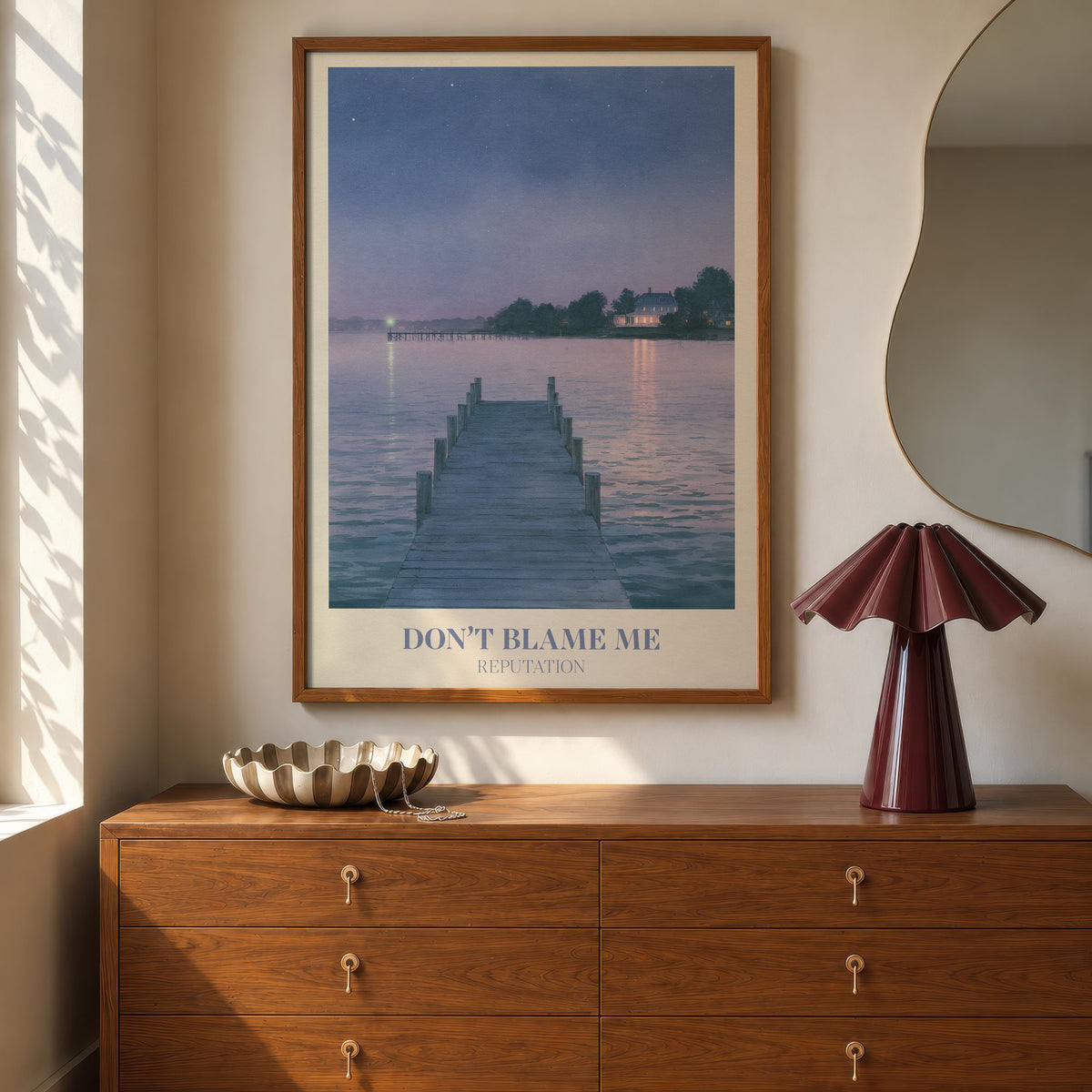 Don’t Blame Me Taylor Swift print of a jetty on a lake at dusk, hung above a walnut dresser beside a wavy mirror and a pleated lamp