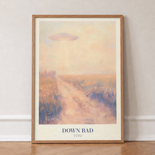Down Bad Taylor Swift print of a UFO beaming light over a dusty track through golden fields, in an oak frame, leaning against a wall on a herringbone floor