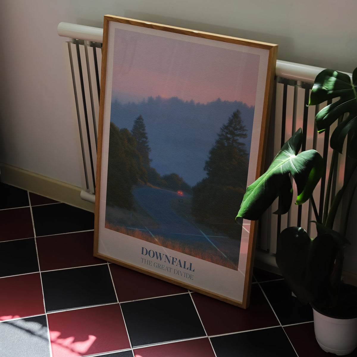 Downfall Noah Kahan print of a winding road through misty pine hills at dusk, framed on a kitchen floor with red and black tiles
