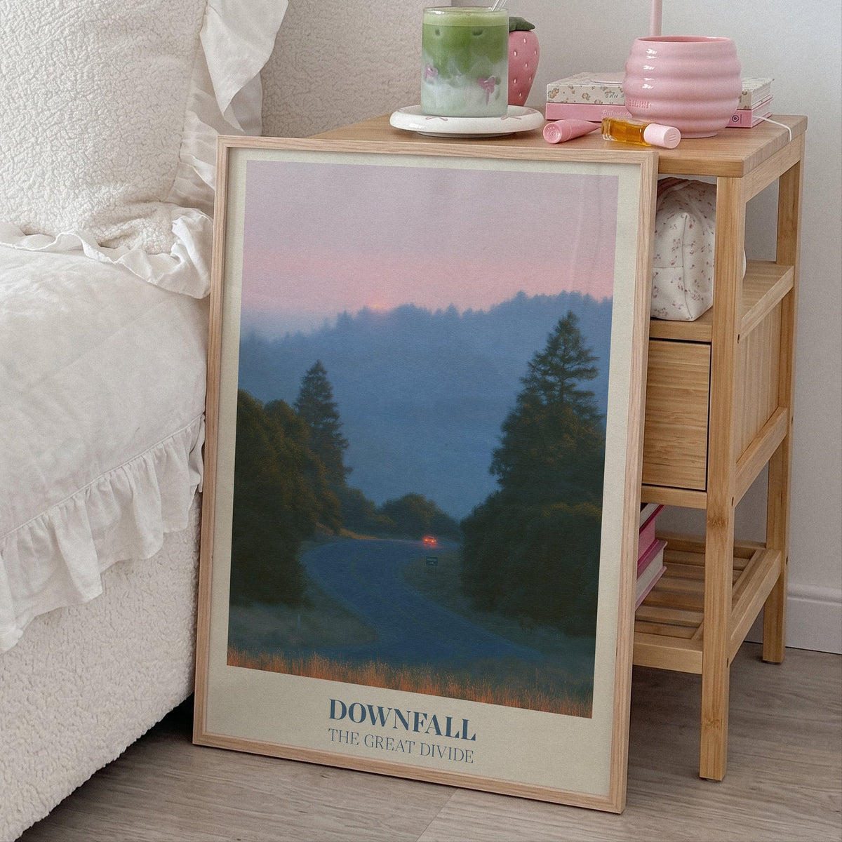 Downfall Noah Kahan print of a winding road through misty pine hills at dusk, framed, leaning beside a bed and a bamboo nightstand