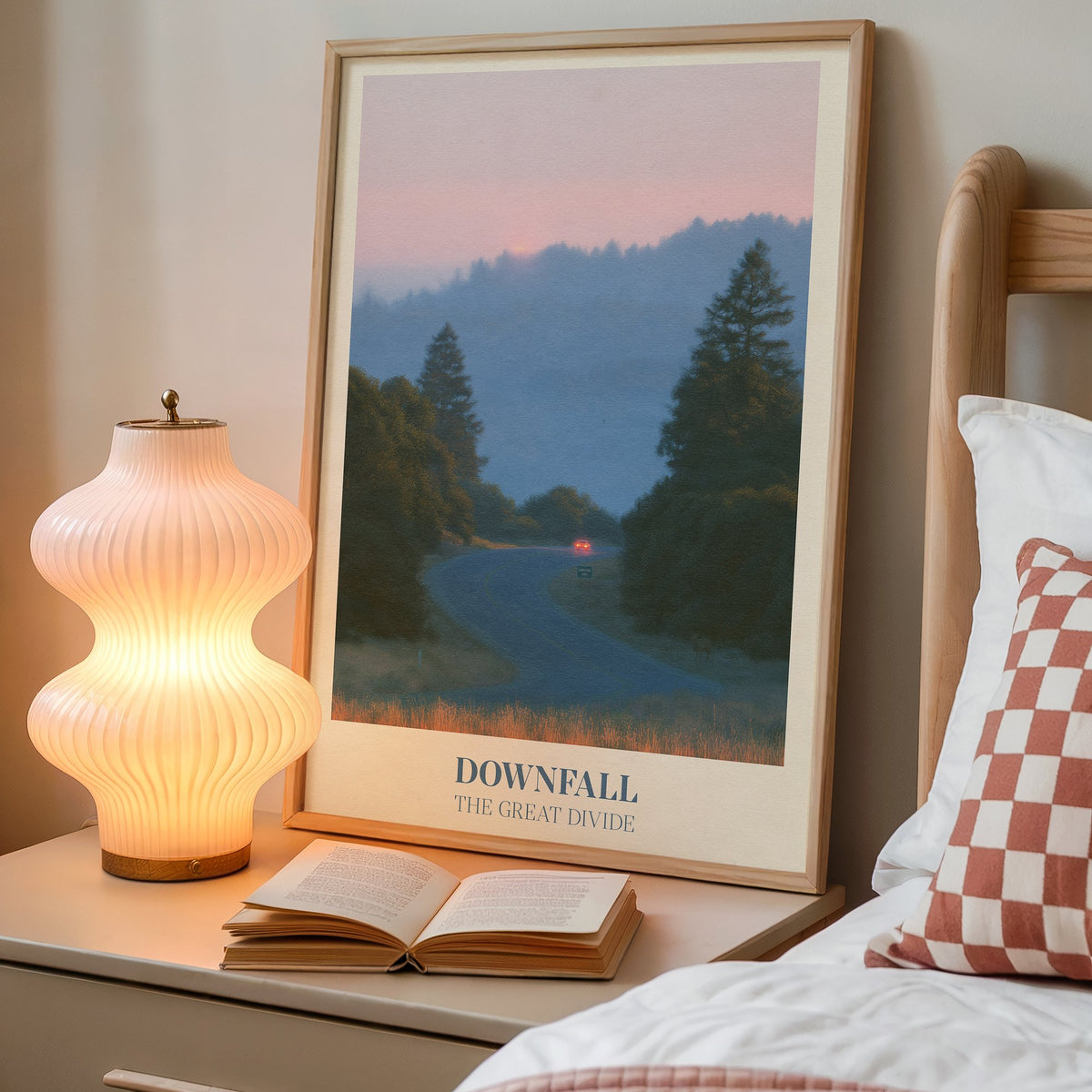 Downfall Noah Kahan print of a winding road through misty pine hills at dusk, framed on a bedside table next to a lamp
