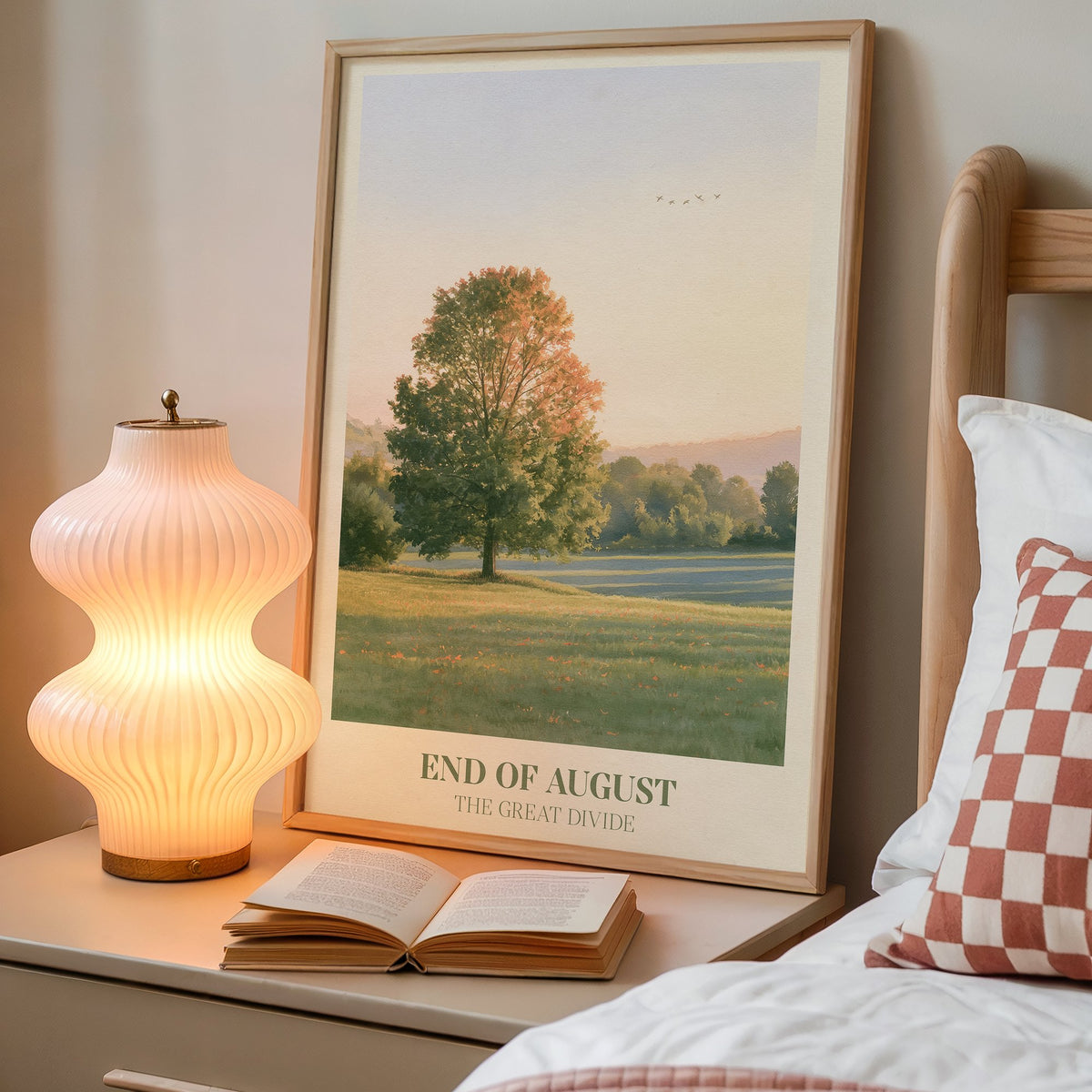 End of August Noah Kahan print of a lone tree in a late-summer field, framed on a bedside table beside a lamp