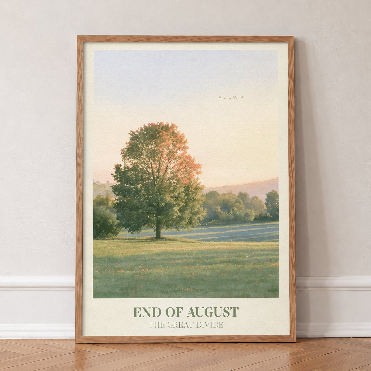 End of August Noah Kahan print of a lone tree in a late-summer field, in an oak frame, leaning against a wall on a herringbone floor
