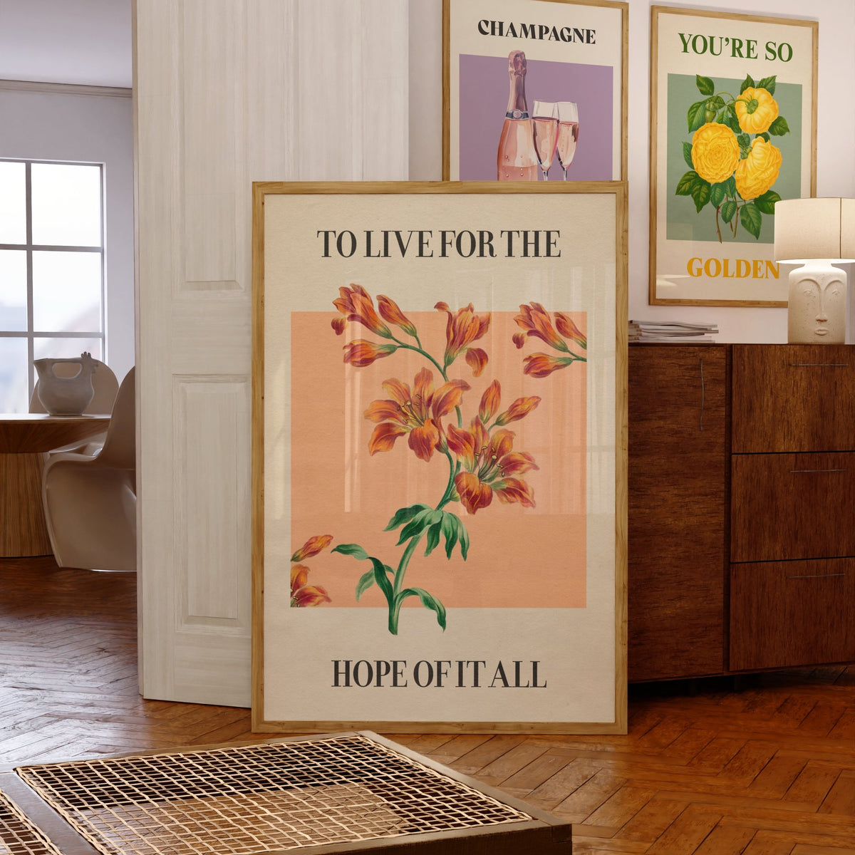 For The Hope Of It All Taylor Swift print of orange lilies on a peach square, framed, leaning against a chest of drawers