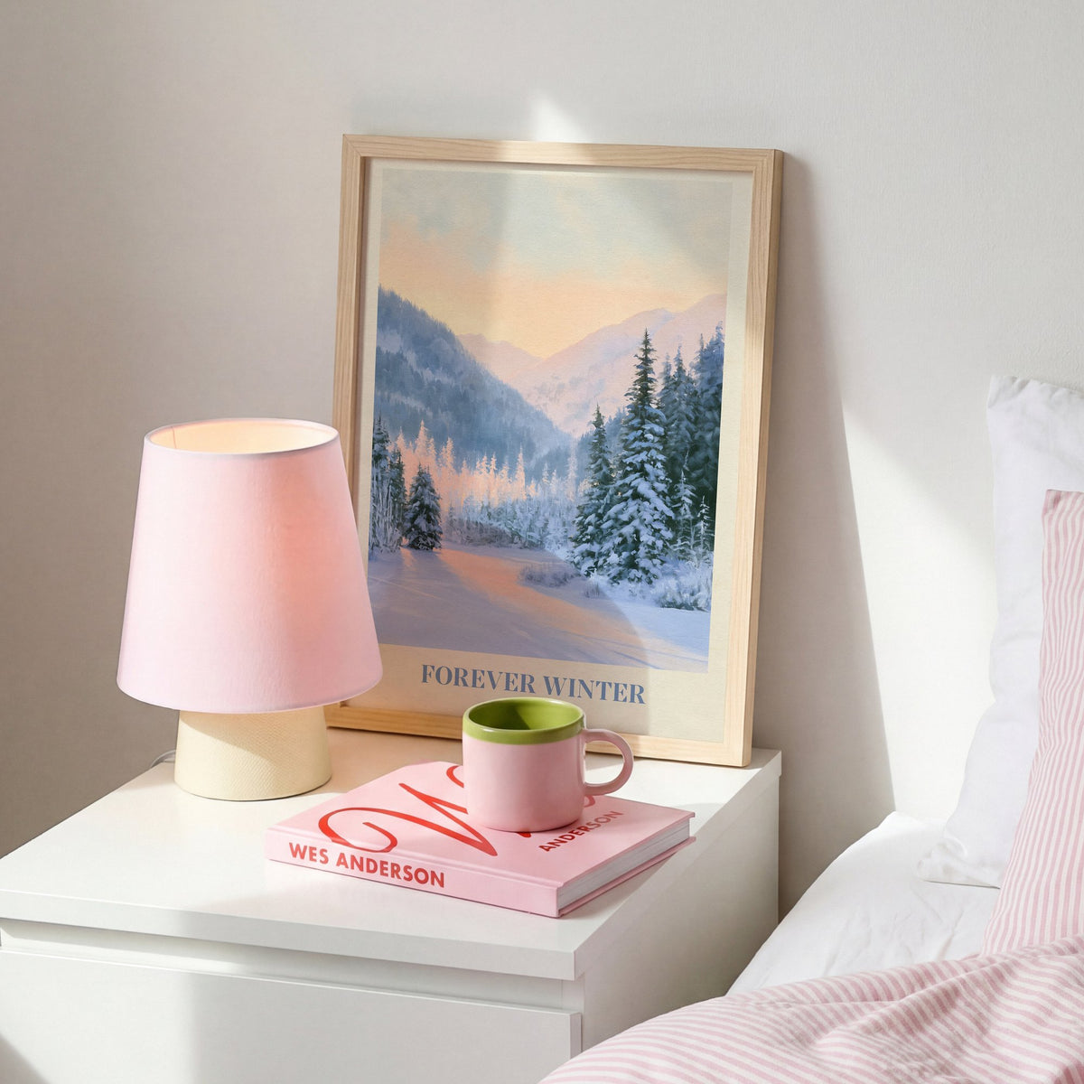 Forever Winter Taylor Swift print of snowy pines in a mountain valley, on a white bedside table beside a pink lamp