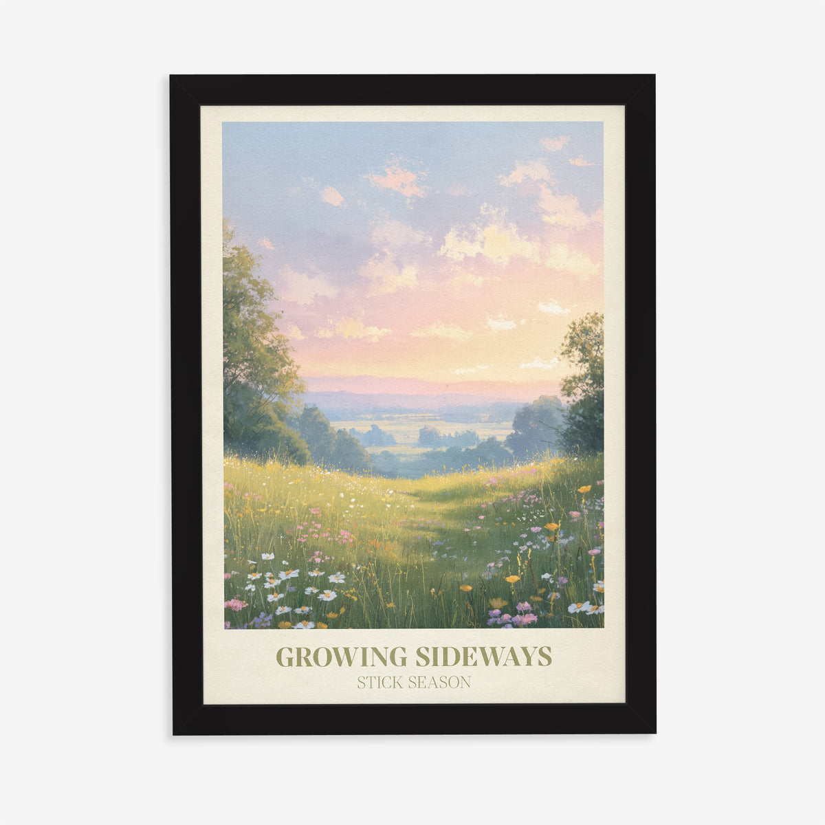 Growing Sideways Noah Kahan print of a wildflower meadow at sunset, in a black frame on a plain wall