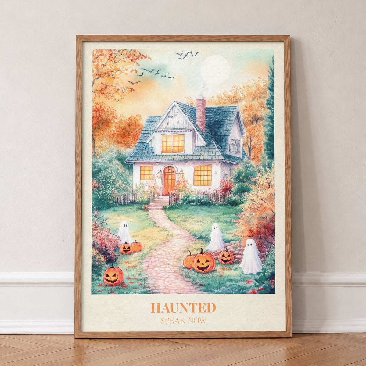 Haunted Taylor Swift print of a cottage with friendly ghosts and jack-o-lanterns on the lawn, in an oak frame, leaning against a wall on a herringbone floor