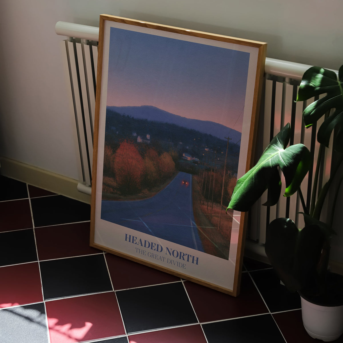 Headed North Noah Kahan print of a country road through autumn trees at dusk, framed on a kitchen floor with red and black tiles