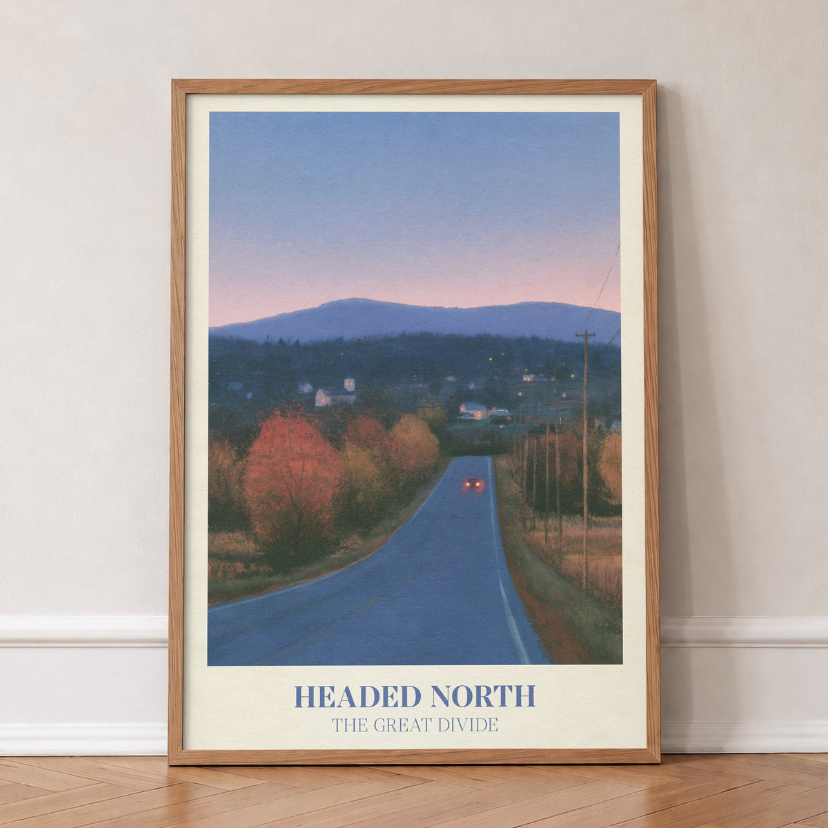 Headed North Noah Kahan print of a country road through autumn trees at dusk, in an oak frame, leaning against a wall on a herringbone floor