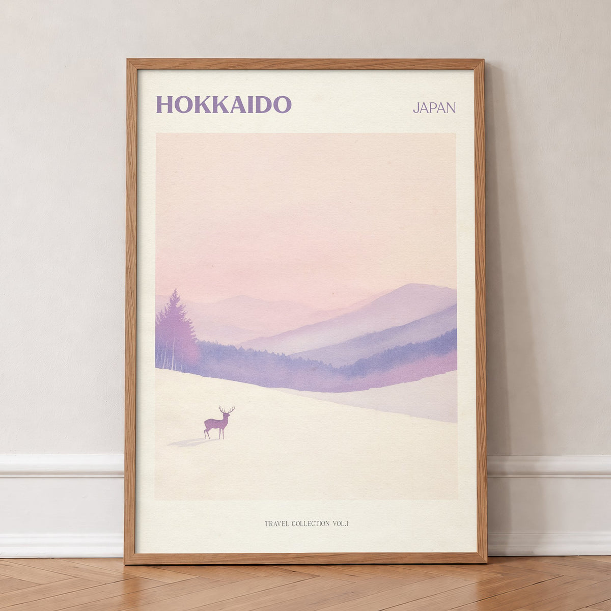 Hokkaido travel print of a lone deer in deep snow below soft pink and lilac hills, in an oak frame, leaning against a wall on a herringbone floor