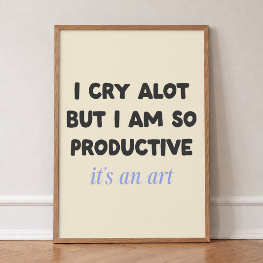 I Cry A Lot But I’m So Productive Taylor Swift lyric print of black and blue lettering on cream, in an oak frame, leaning against a wall on a herringbone floor