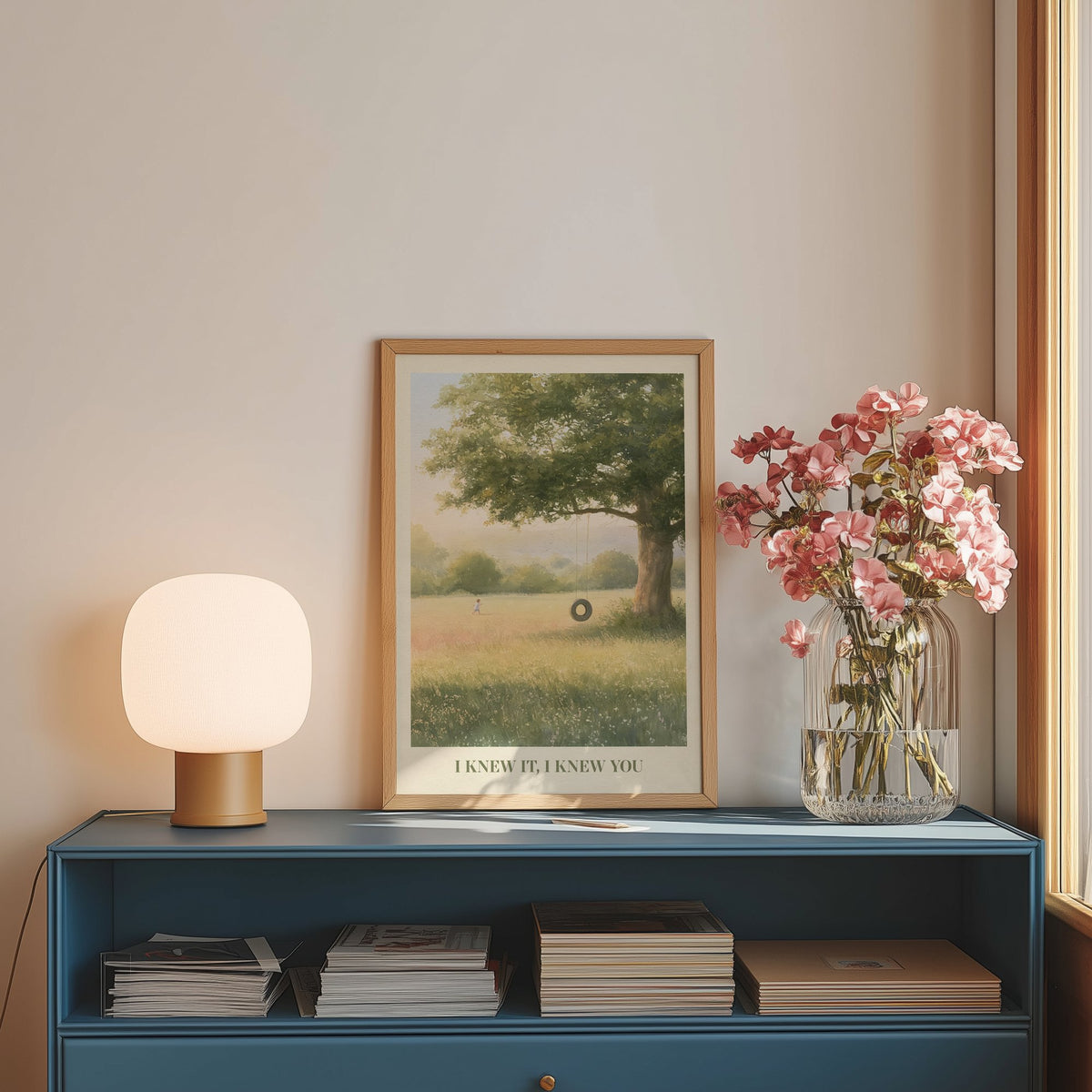 I Knew It, I Knew You Taylor Swift print of a tyre swing on an old oak, on a blue sideboard with a lamp and flowers