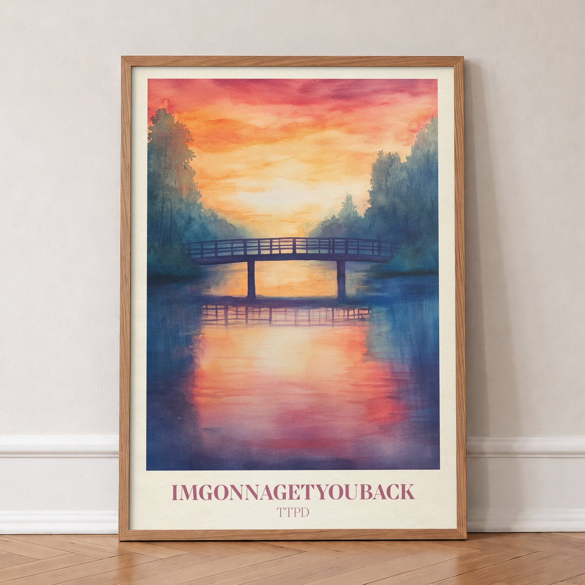 Imgonnagetyouback Taylor Swift print of a footbridge over a river at a fiery sunset, in an oak frame, leaning against a wall on a herringbone floor