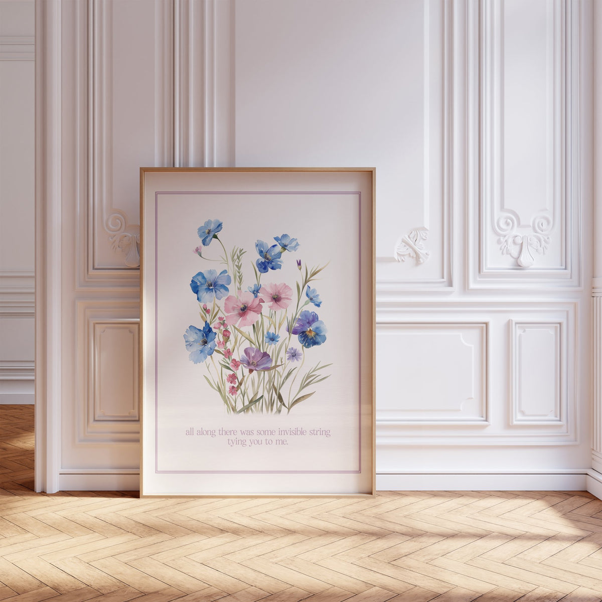 Invisible String Botanical Taylor Swift print of blue and pink wildflowers, framed, leaning against a white panelled wall