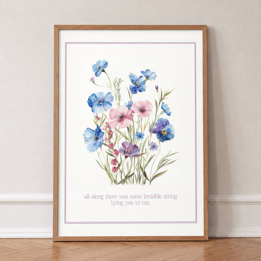 Invisible String Botanical Taylor Swift print of blue and pink wildflowers, in an oak frame, leaning against a wall on a herringbone floor
